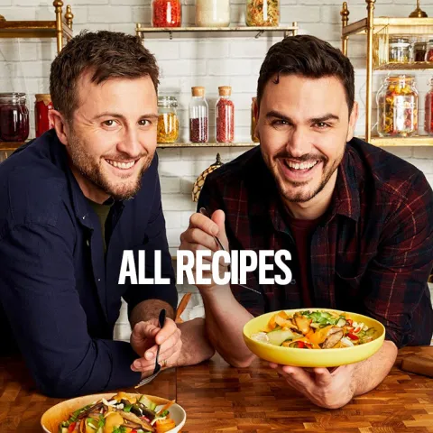 two men leaning over a kitchen bench holding a plate of food with the text ALL RECIPES superimposed